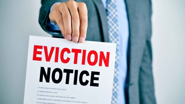 person in a business suit holding up a paper with the word eviction notice